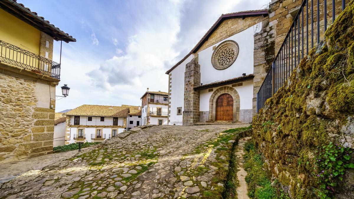 Old stone church next to traditional old houses from the village of Candelario in Salamanca, Spain