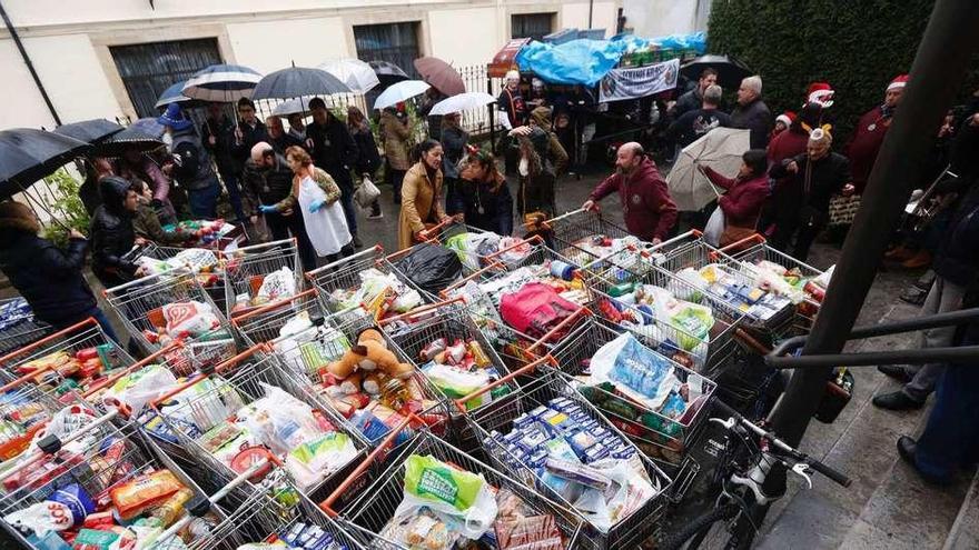 Carritos con alimentos en la Cocina Económica y, al fondo, la parihuela de los costaleros de la Hermandad de los Estudiantes.