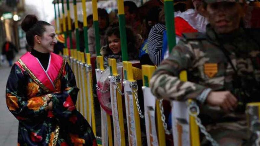 A la izquierda, varios niños disfrazados disfrutan del paseo por las calles de la capital subidos al tren del carnaval. A la derecha, tres pequeñas princesas se resguardan con sus paraguas de la lluvia.