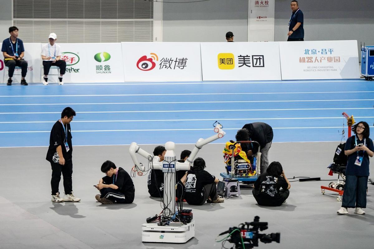 Técnicos se sientan con un robot de servicio durante los Juegos Mundiales de Robots Humanoides en Pekín, China, el viernes 15 de agosto de 2025. El evento se celebra hasta el 17 de agosto. Fotógrafo: Qilai Shen/Bloomberg