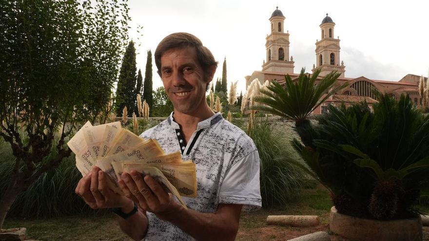 Toño Piñeiro muestra un fajo de antiguos billetes de 5.000 pesetas en el lardín del Museu de la Ciutat Casa de Polo, con los campanarios de la basílica de Sant Pasqual de fondo.