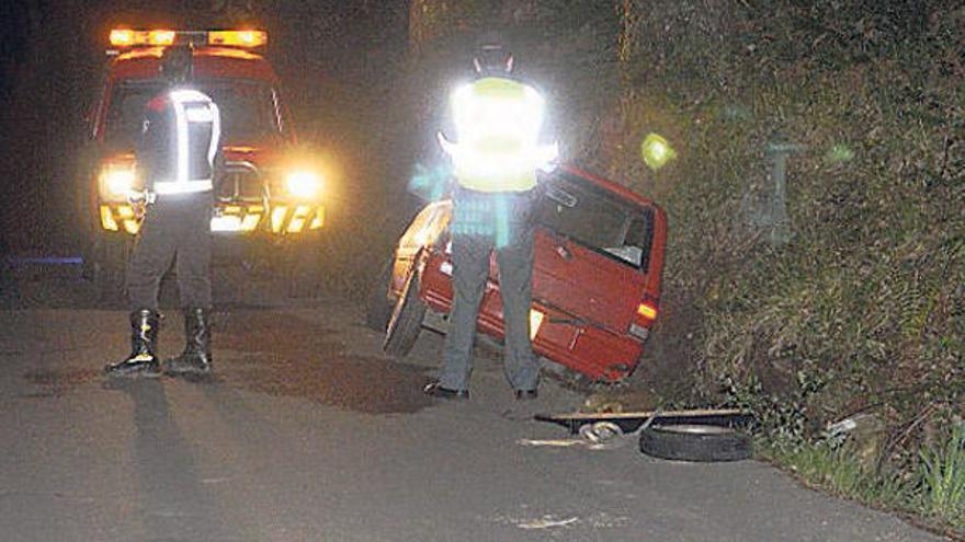 Dos agentes ante el vehículo, en la cuneta de la carretera.  // Noé Parga