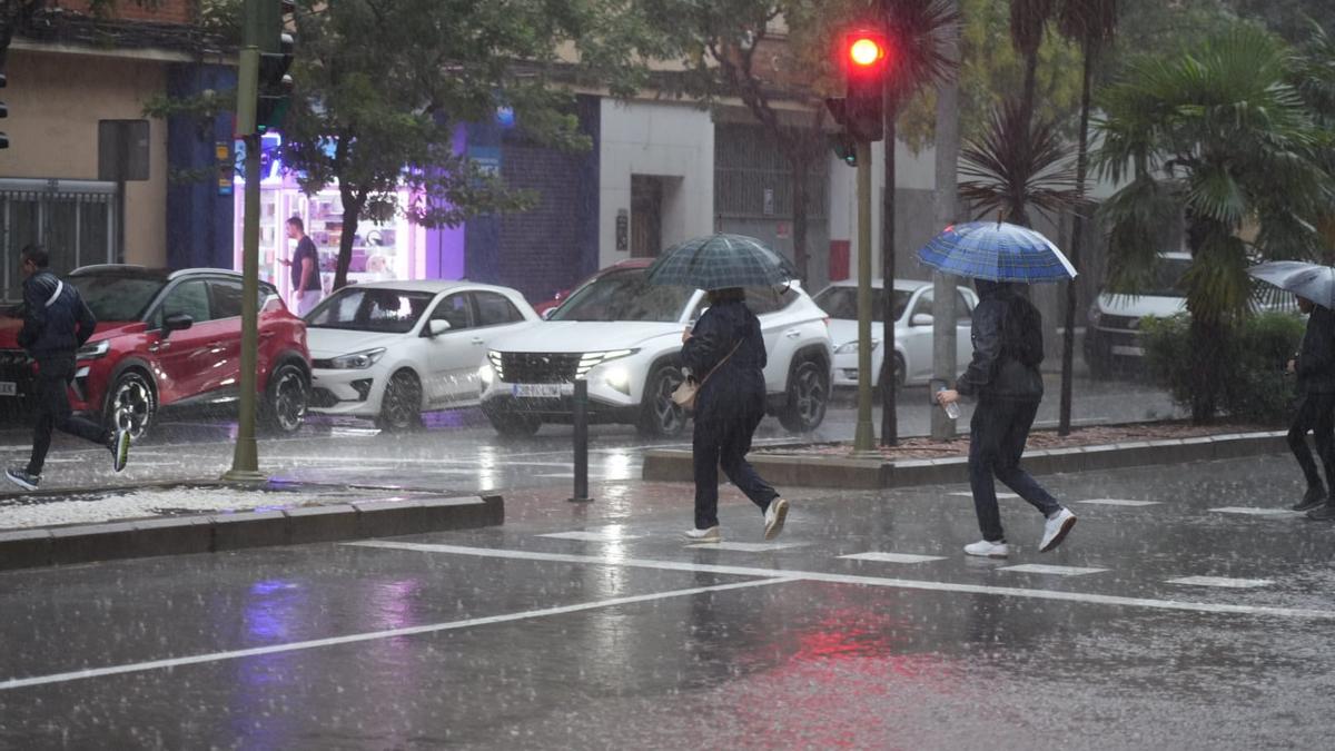 Castellonenses resguardándose de la lluvia con paraguas.