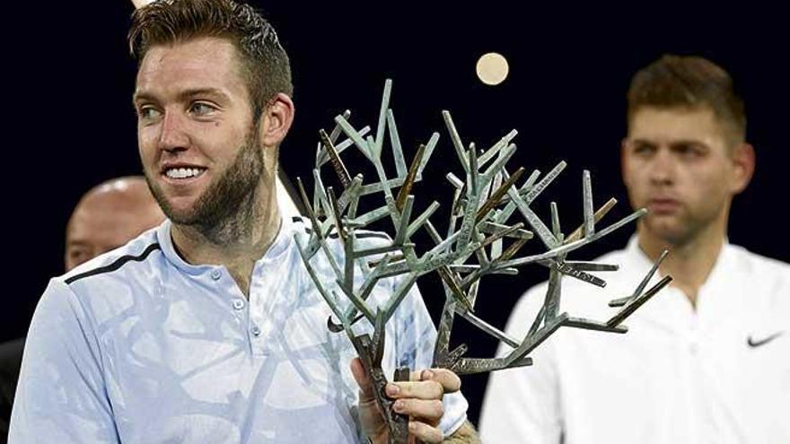 Jack Sock exhibe su trofeo, con Krajinovic al fondo.