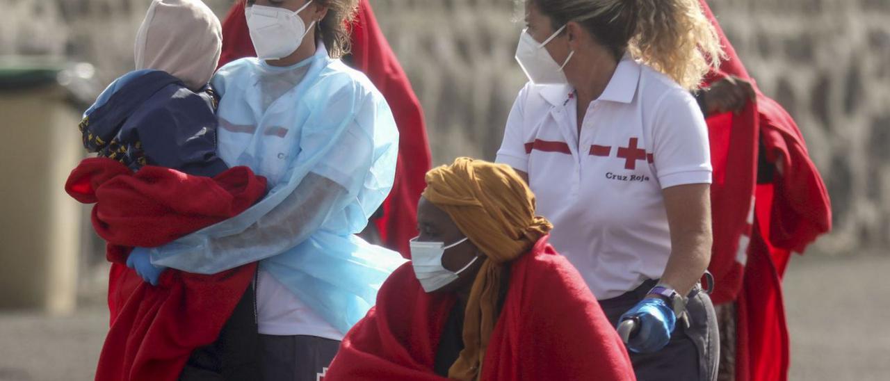 Dos trabajadoras de la Cruz Roja ayudan a una familia de migrantes, ayer, en Lanzarote. | | ADRIEL PERDOMO (EFE)