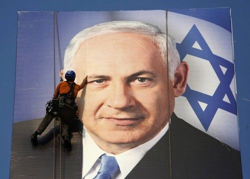 A worker installs a banner depicting Israel's Prime Minister Netanyahu in Tel Aviv