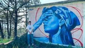 El artista vigués Beis331 posa junto a uno de sus murales.