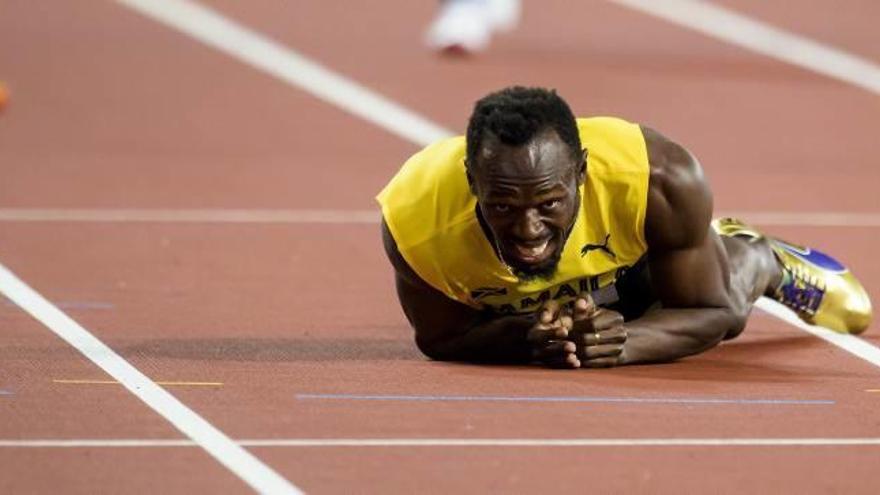 El jamaicano Usain Bolt yace en el suelo del estadio olímpico de Londres tras lesionarse anoche en plena carrera en la recta final del relevo 4x100.