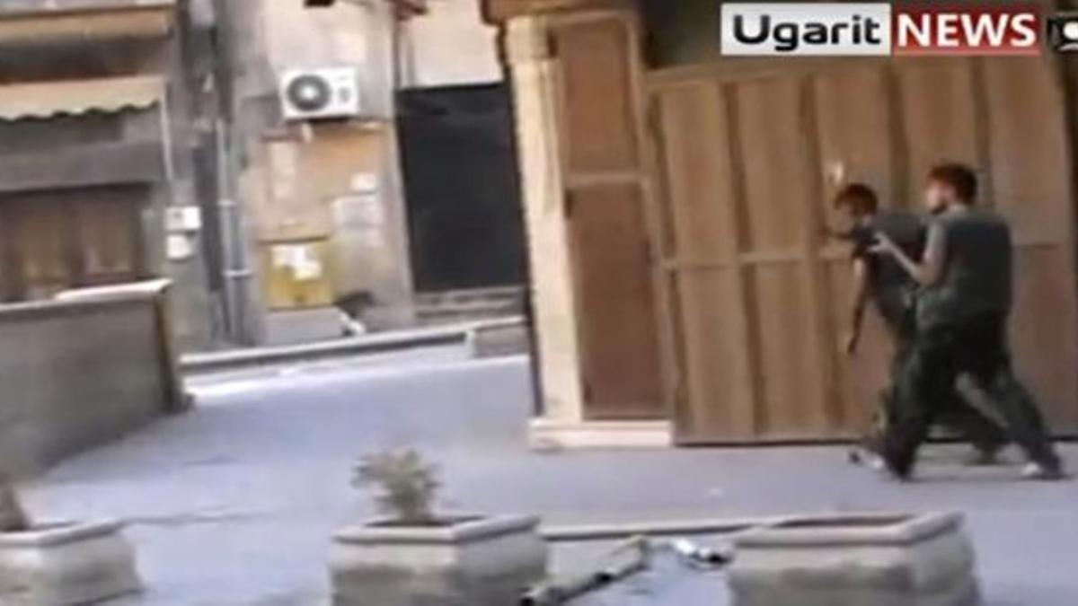 Dos rebeldes se diponen a lanzar granadas de mano en Alepo.