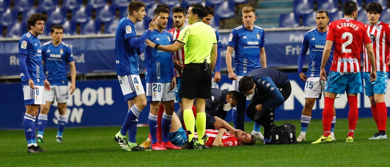 Los jugadores del Oviedo y del Lugo rodean al árbitro, con Barreiro en el suelo. | Luisma Murias