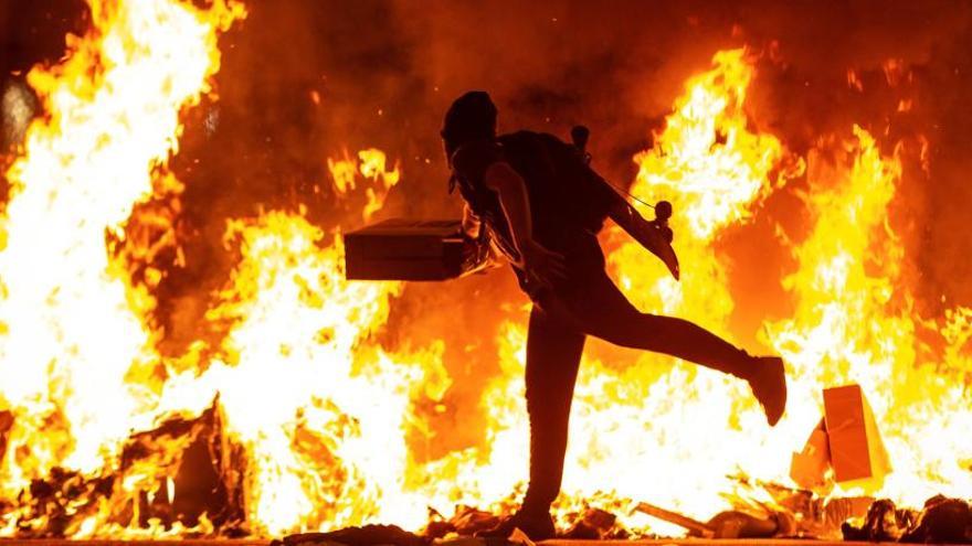 Un manifestante echa al fuego un cartón junto a la Delegación del Gobierno en Barcelona