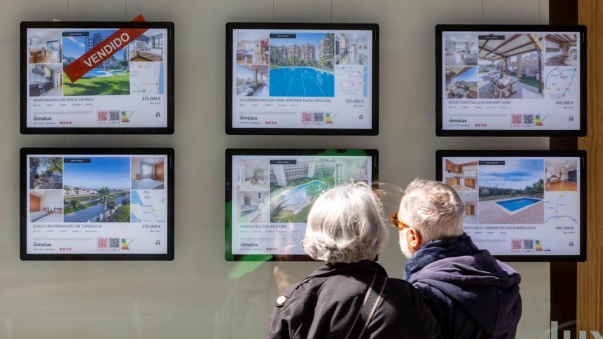 Una pareja se interesa por una de las viviendas anunciadas en una inmobiliaria de Alicante. / Jose Navarro