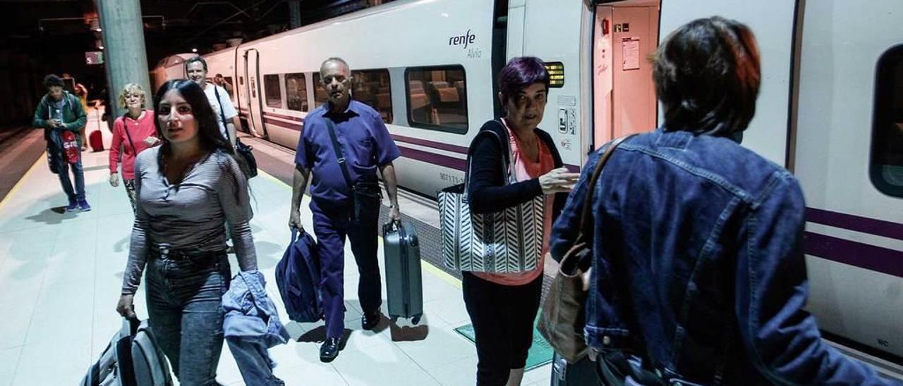 Varias personas bajan de un tren.