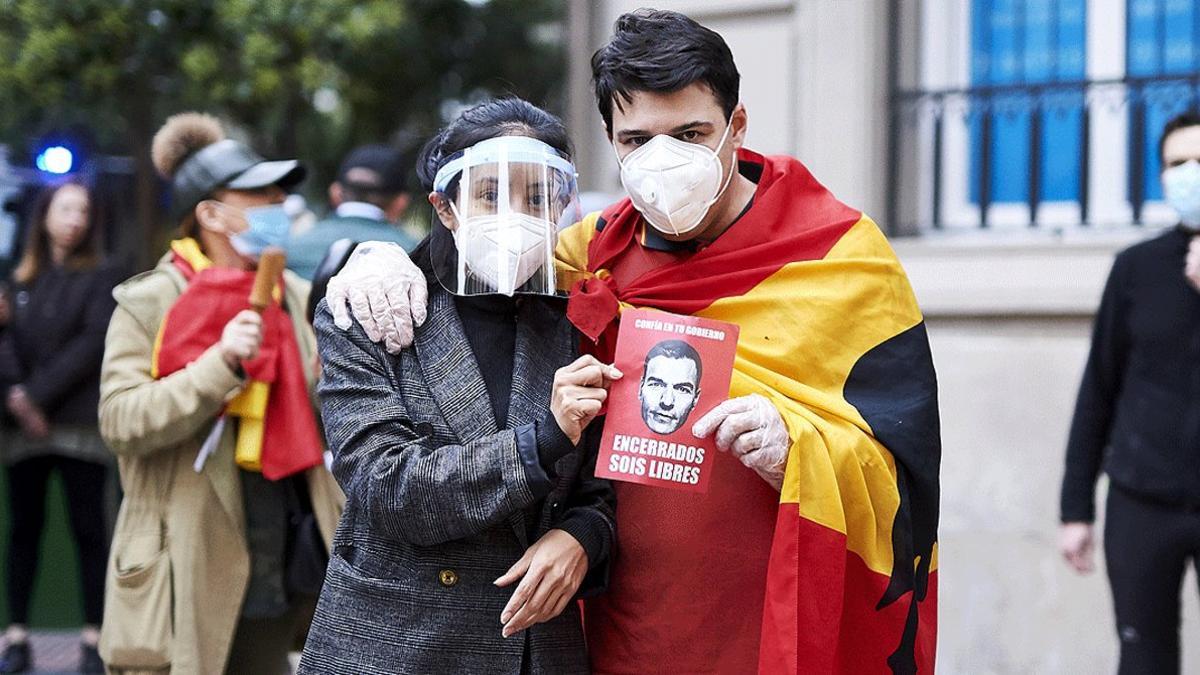 Dos jóvenes posan con un folleto irónico contra Pedro Sánchez durante la protesta de los residentes del barrio de Salamanca de Madrid contra la gestión de la crisis del coronavirus por parte del Gobierno, el 14 de mayo