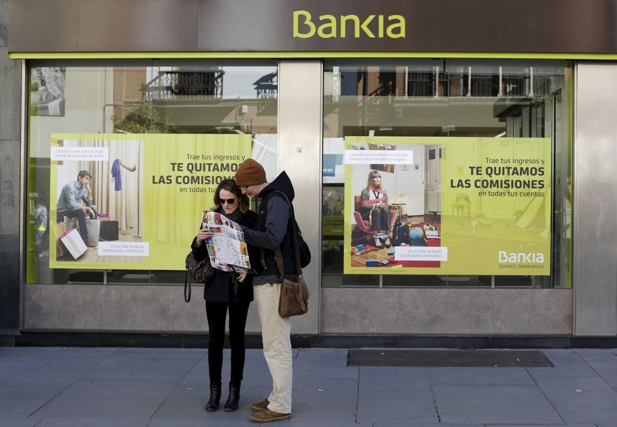 Tourists look at a city map in front of a Bankia bank branch in the Andalusian capital of Seville, southern Spain February 17, 2016. REUTERS/Marcelo del Pozo