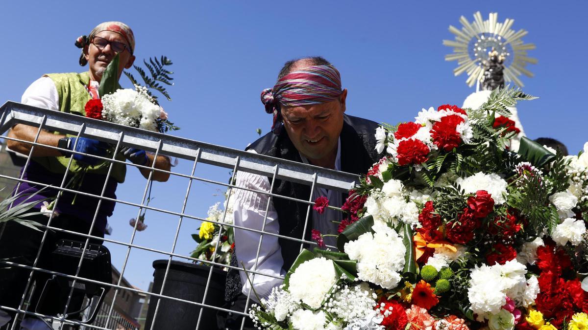 Un trabajador coloca las flores en el manto de la Virgen del Pilar