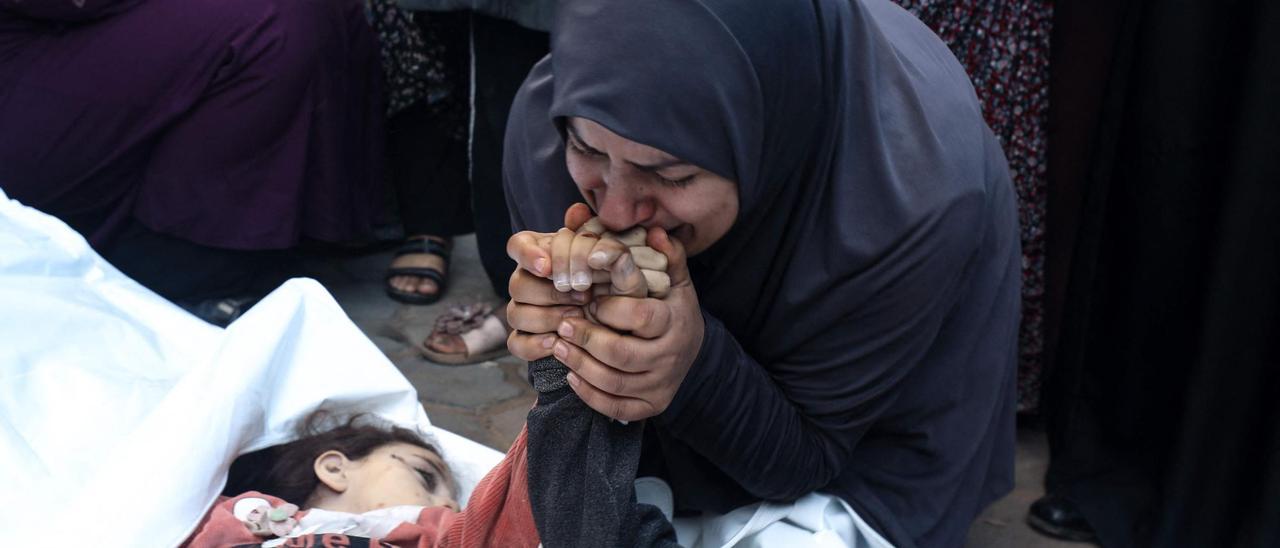 La madre de dos mellizos de 8 años fallecidos en un bombardeo israelí besa sus manos en el hospital Al Aqsa de Gaza, el pasado 29 de diciembre.