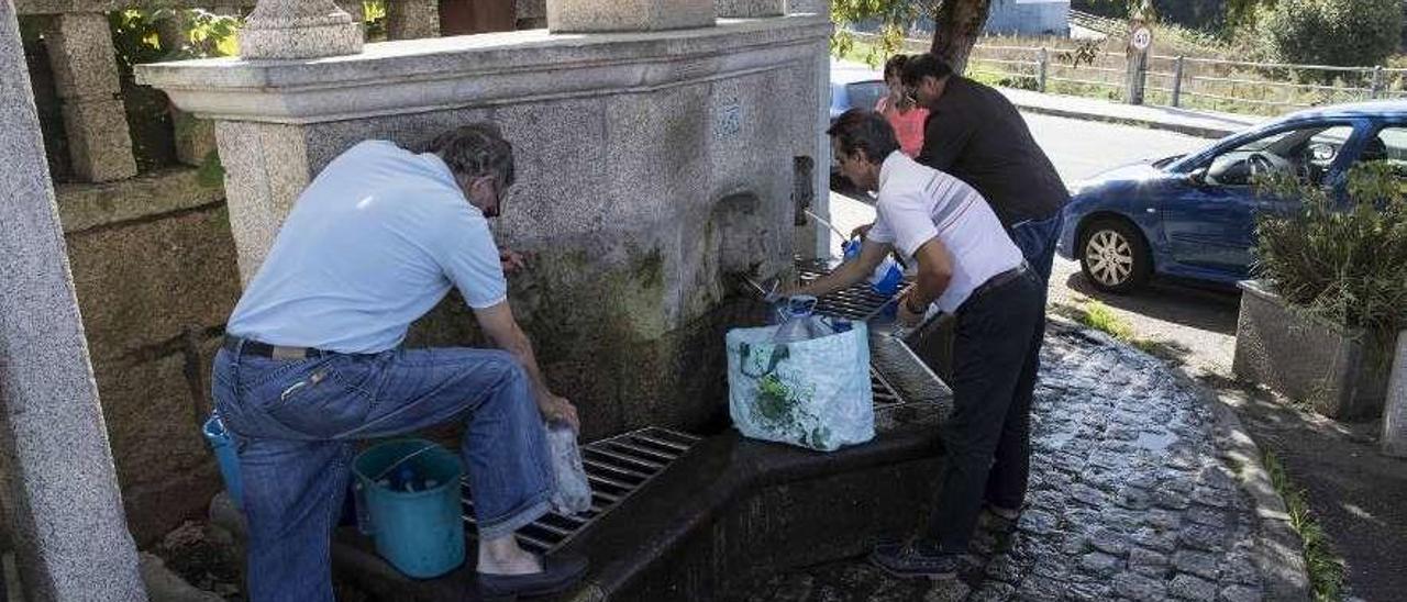 Vecinos recogiendo agua de una fuente en Bembrive (Vigo). // Cristina Graña