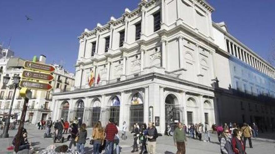 Varias personas pasean ante la fachada del Teatro Real en Madrid