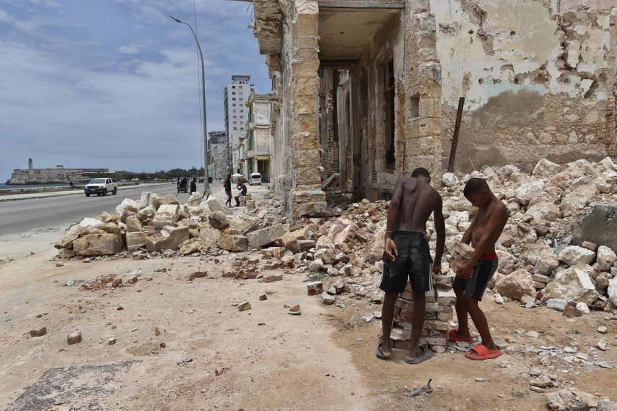Dos niños acarrean piedras en un edificio en ruinas en el Malecón de La Habana.