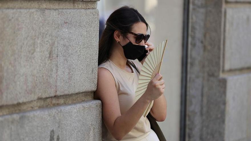 Una mujer con mascarilla y abanico.