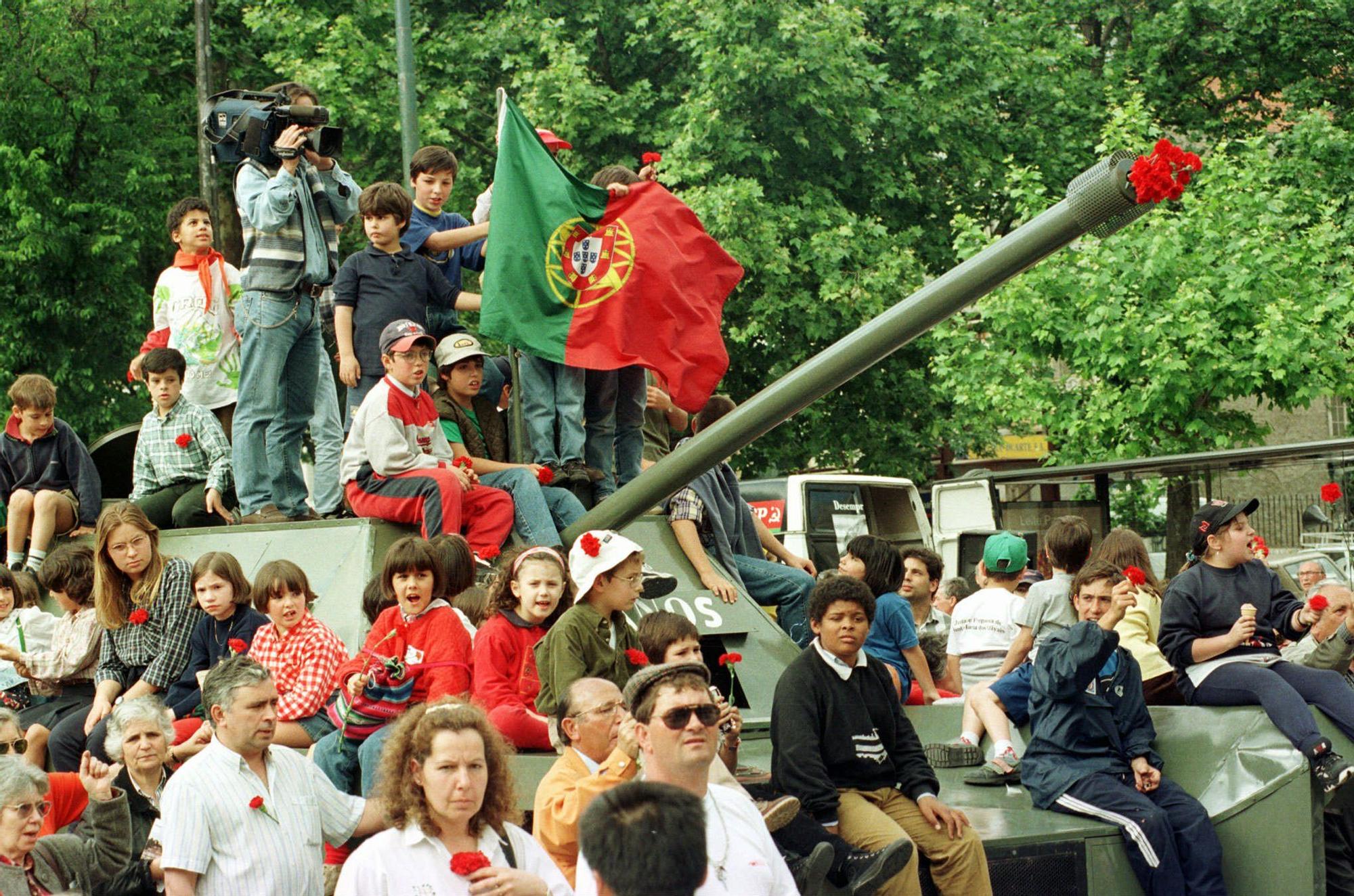Celebración del 23 aniversario de la Revolución de los Claveles en Lisboa.Kids on top of a military tank hold up carnations singing during the demonstration celebrating the 23th anniversary of the Carnations Revolution in Lisbon's Liberdade Avenue, Friday April 25 1997. Carnations are the symbol of the 1974 Portuguese Revolution which was been made by the military, ending with 48 years of dictatorship government. (AP Photo/Luisa Ferreira) / Tanque.