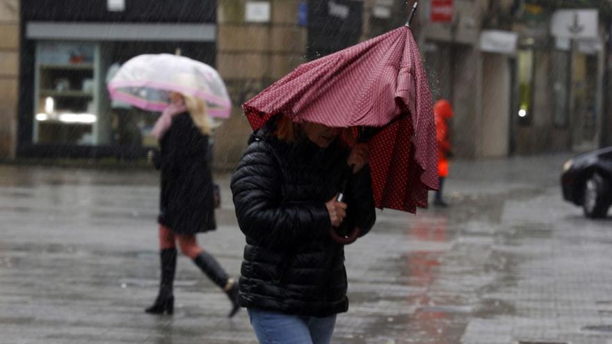 Una mujer se cubre con un paraguas ya roto de las fuertes precipitaciones de los últimos días. |   // G. S.