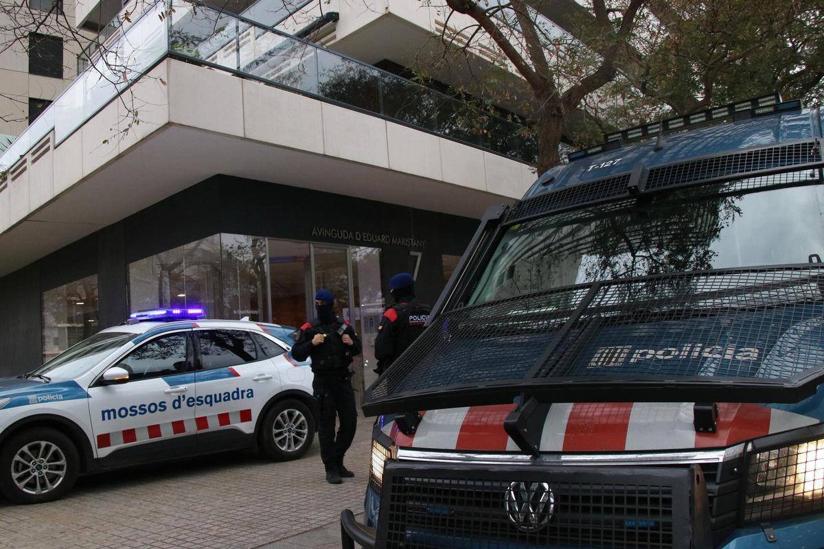 Els vehicles del cos dels Mossos a l'accés a l'edifici on s'ha escorcollat i detinguts a dues persones