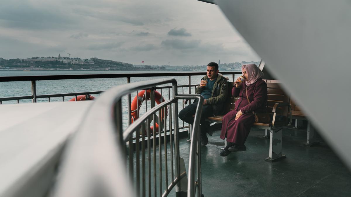 Un pasajero y una pasajera bebén su café con Estambul al fondo.