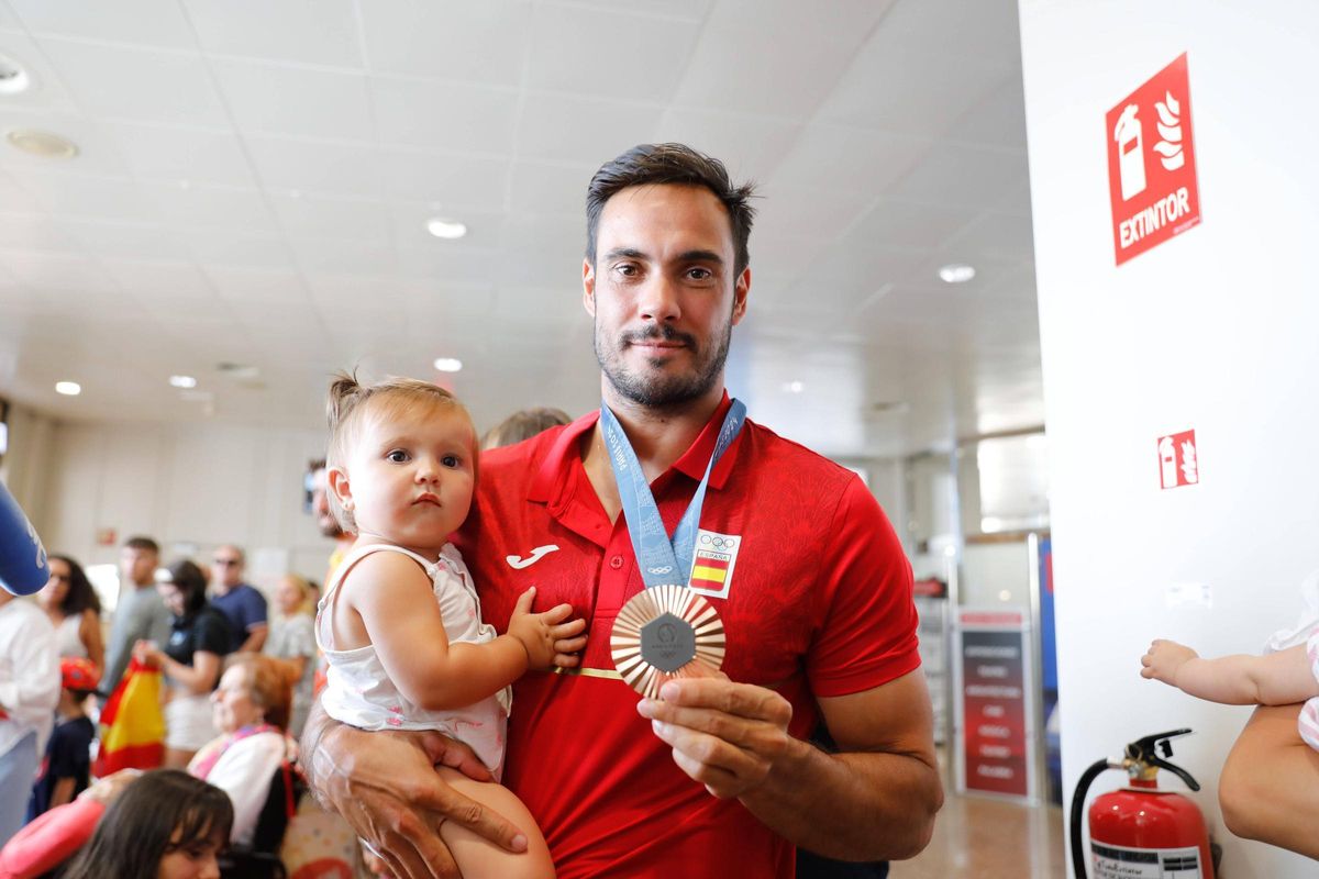 Germade sostiene la medalla con su hija en brazos.