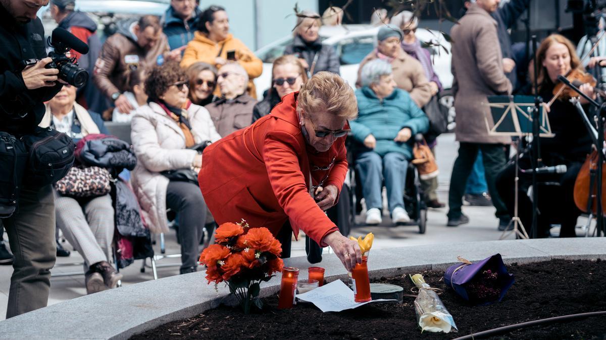 Una mujer enciende una vela durante un homenaje por las víctimas del atentado del 11M en su 20 aniversario, en la placa conmemorativa de la calle Téllez, a 11 de marzo de 2024, en Madrid (España). La ofrenda foral ha sido organizada por la Asociación 11-M