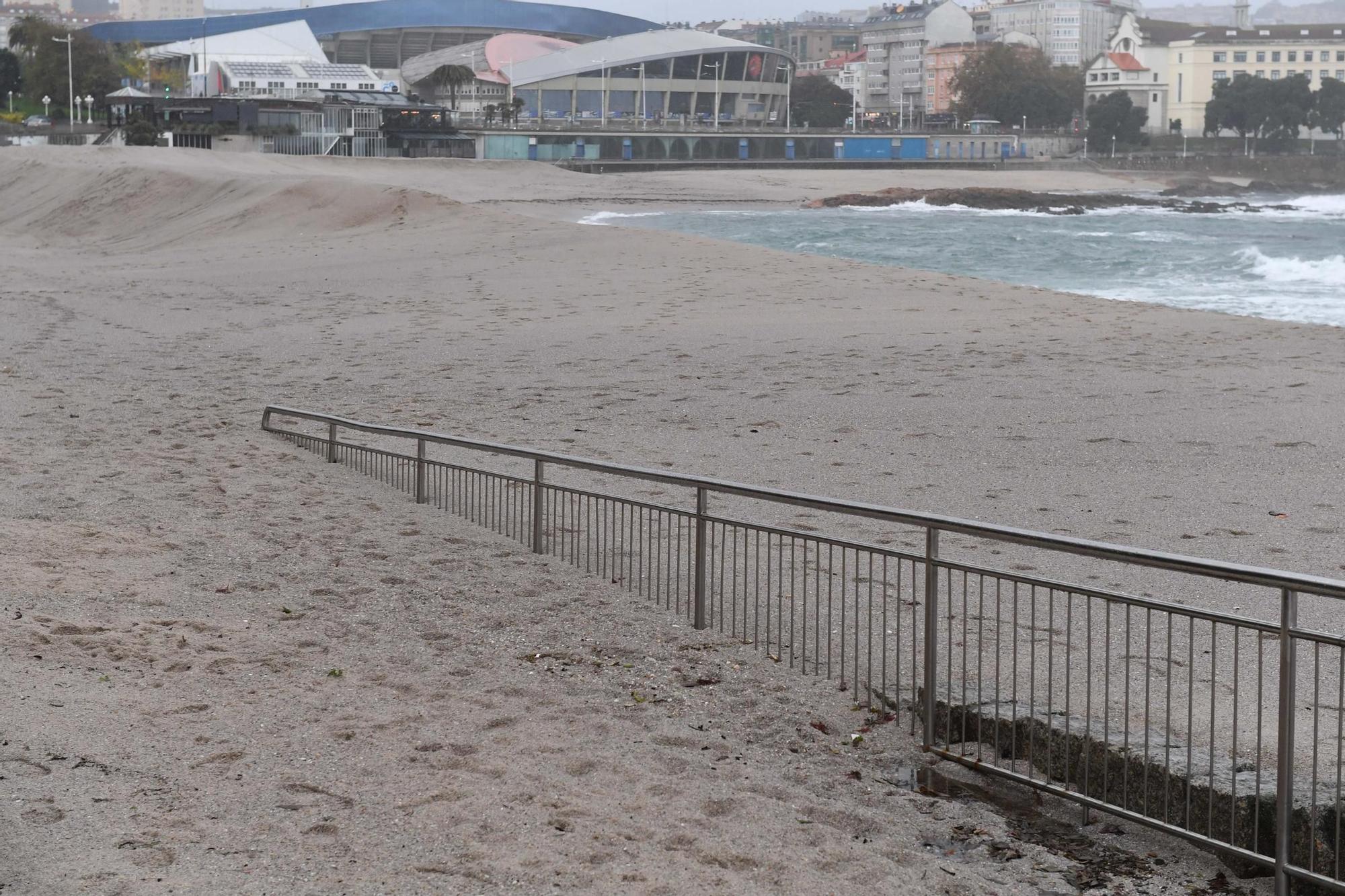 La fuerza del oleaje arrastra la duna de Riazor y llega al paseo marítimo