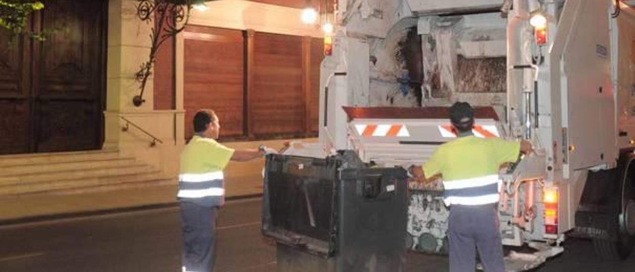 Operarios de la recogida de residuos urbanos vacían uno de los contenedores en la ciudad de Orihuela.