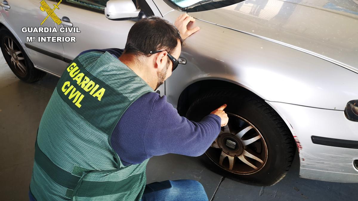 Un agente de la Guardia Civil comprueba uno de los pinchazos en un neumático.