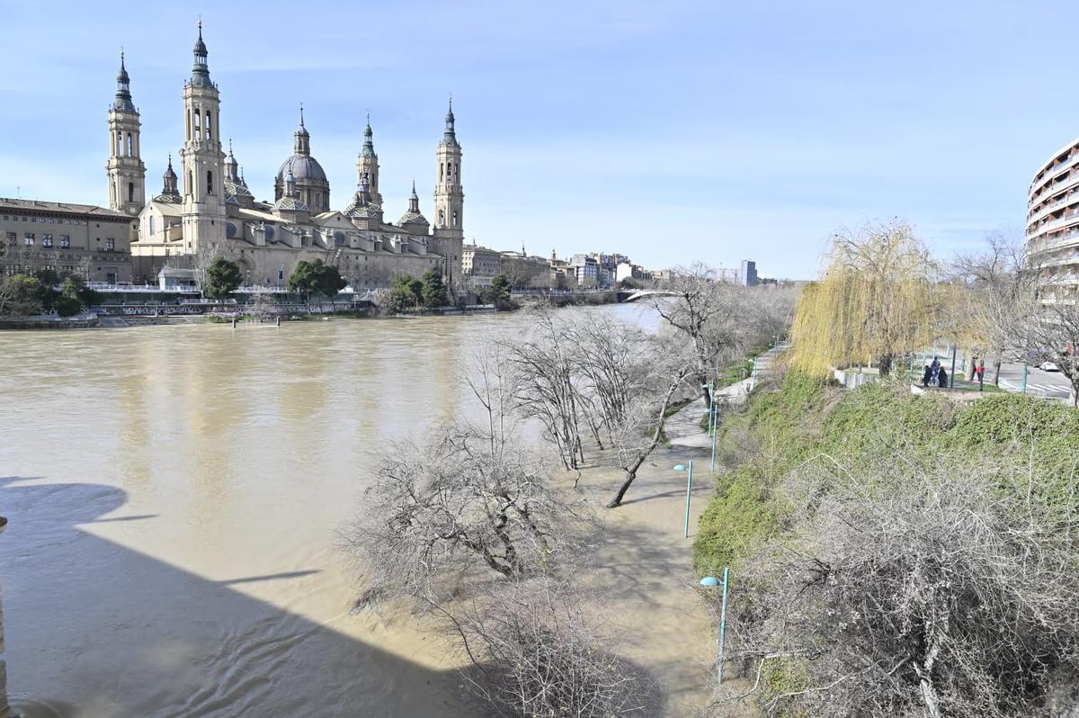 El Ebro a su paso por Zaragoza, con la basílica del Pilar al fondo, y las riberas ya anegadas este domingo.