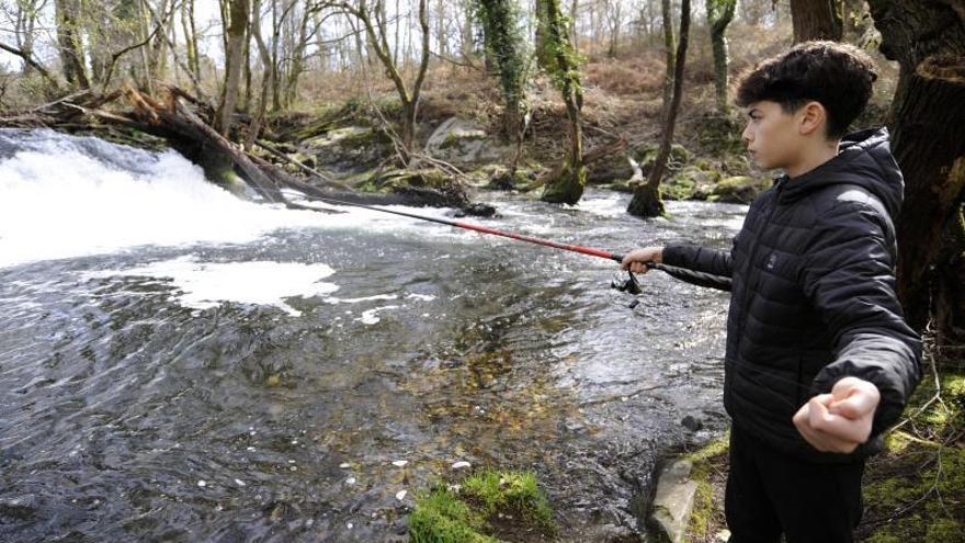 Un joven pesca en el río Asneiro, a su paso por Mouriscade, el pasado mes de marzo. |   // BERNABÉ/JAVIER LALÍN