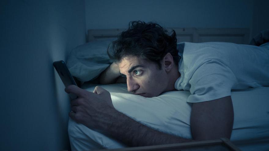 Un joven usa el teléfono en la cama.