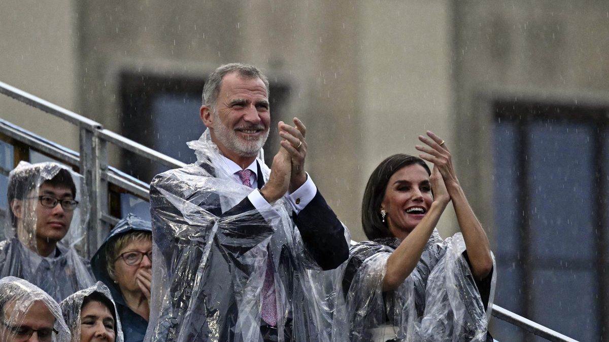 Los reyes de España, Felipe VI y Letizia, con chubasquero durante la ceremonia de París 2024.
