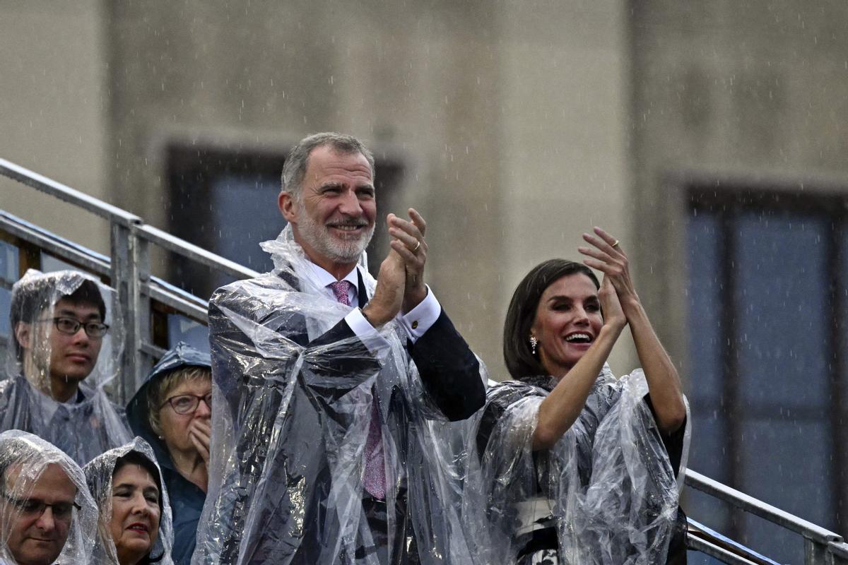 Los reyes de España, Felipe VI y Letizia, con chubasquero durante la ceremonia de París 2024.