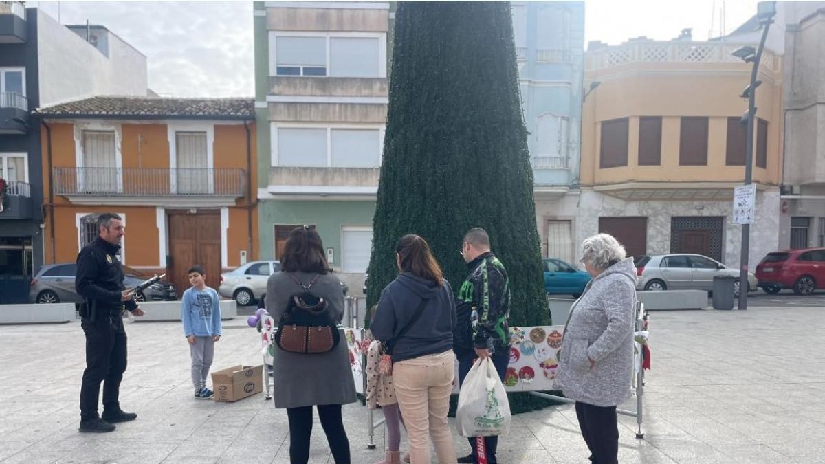 Varios vecinos decoran de nuevo el árbol navideño.