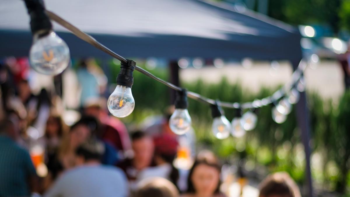 Hanged lamps at outdoor restaurant with multiple visitors on the background, BBQ