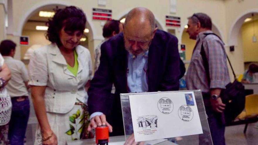 La directora de Correos de Gijón, María Luisa Montes, con Luis Rollán, imprimiendo el primer matasellado.