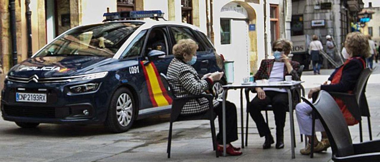 Una patrulla de la Policía Nacional, junto a una terraza del Antiguo que cumple con la normativa establecida.