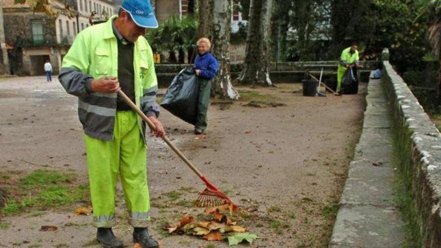 Tres operarios municipales, realizando labores de limpieza y mantenimiento junto al monasterio.  // G. S.