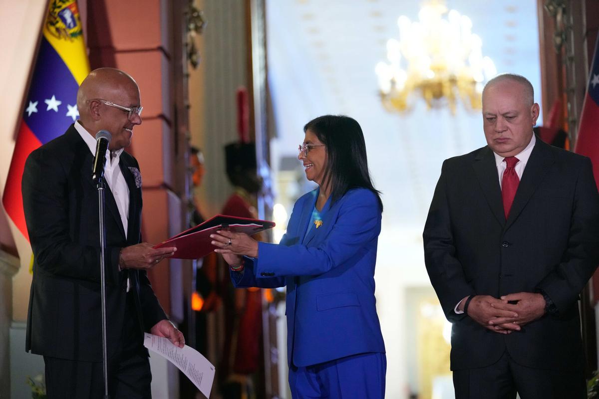 El presidente de la Asamblea Nacional, Jorge Rodríguez, entrega un proyecto de ley de amnistía aprobado por los legisladores a su hermana, la presidenta interina Delcy Rodríguez, mientras el ministro del Interior, Diosdado Cabello, observa en el Palacio de Miraflores en Caracas