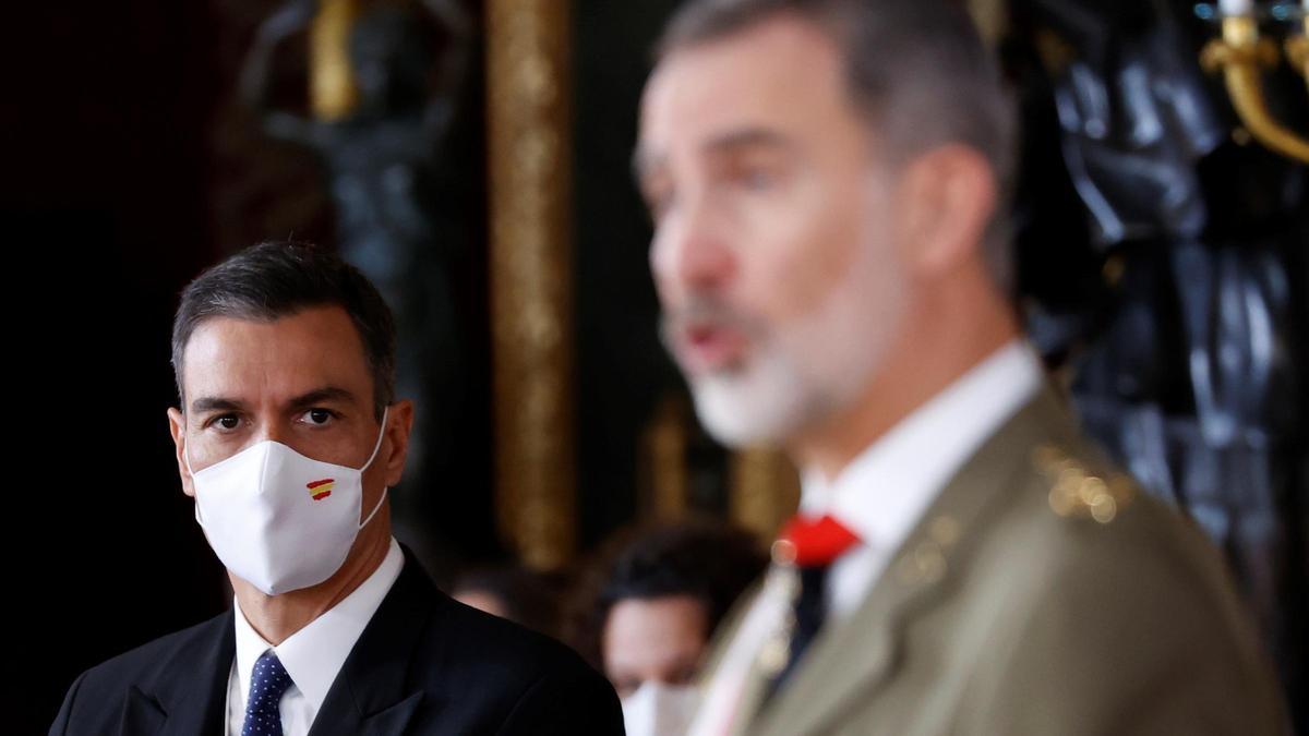 Pedro Sánchez, con mascarilla con la bandera de España, atendiendo al Rey, durante su discurso.