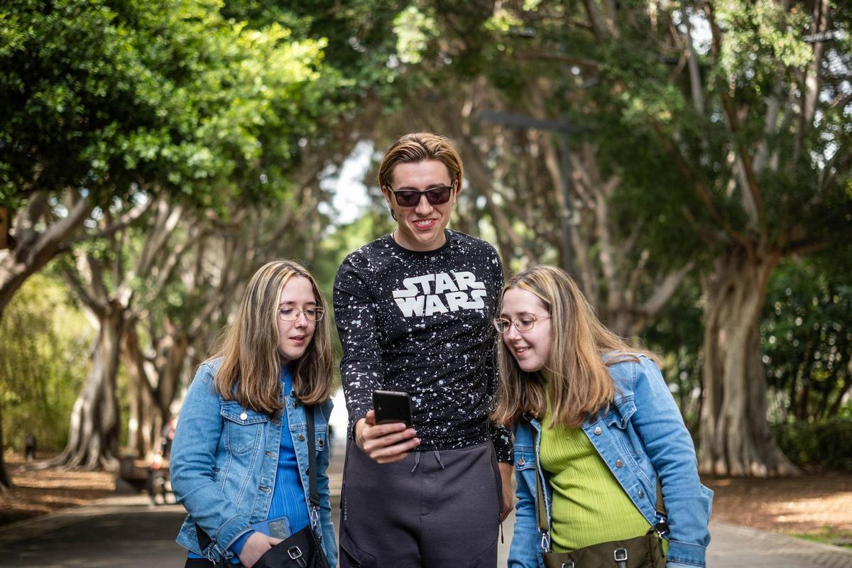 Las hermanas Aymara y Nayara Mendoza observan la app diseñada por Daniel Comín, que se sitúa  en el centro.