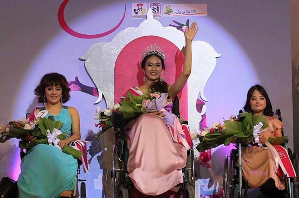 La nova ’Miss cadira de rodes’, Pattarawan Panicha, saluda el públic flanquejada per la primera i la segona dama d’honor, en el certamen de bellesa celebrat a Bangkok (Tailàndia).