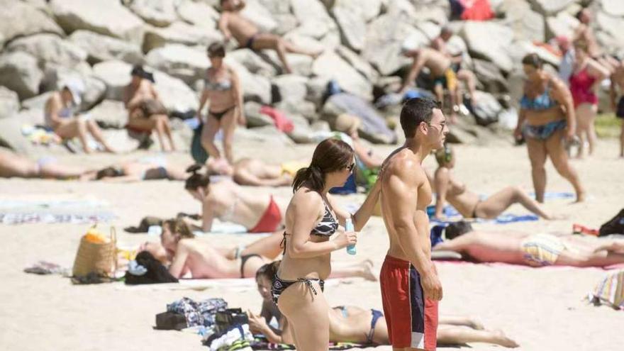 Bañistas utilizan protector solar en la playa de Oza.