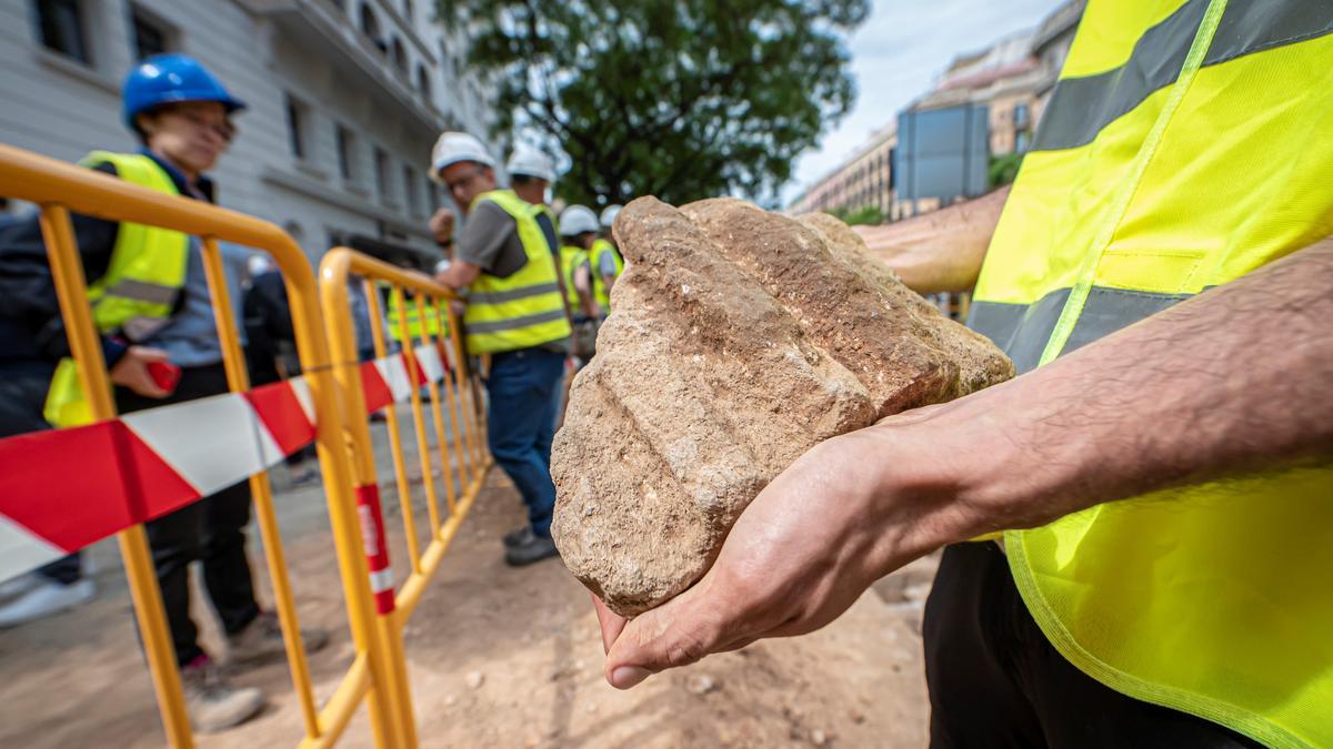 Excavación de una necrópolis tardorromana y tardoantigua en la plaza Antoni Maura. El arqueólogo Joan Garriga sostiene un fragmento de columna romana.